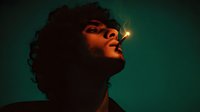 Young African American man with curly hair looking up in dramatic lighting with warm orange and teal color grading for cinematic portrait photography.