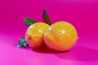 Vibrant apricots with glossy gradient finish and green leaves on bright magenta background, suitable for food packaging and culinary designs.
