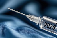 Medical syringe with 2026 number on glass vial against blue fabric background, shallow depth of field macro photography highlighting healthcare concept.