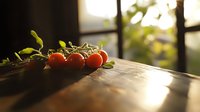 Fresh cherry tomatoes on vine with green leaves lying on rustic wooden surface in warm sunlight, creating moody atmosphere for food photography.