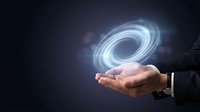 Businessman holding glowing spiral energy orb in palm against dark background, representing innovation, technology, and digital transformation for business concepts.