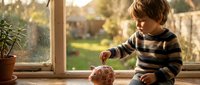 Young toddler in striped sweater playing with toy indoors by sunny window, ideal for parenting and childhood content.