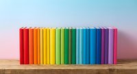 Colorful rainbow books arranged in spectrum order on wooden shelf against gradient background for education and learning concepts.