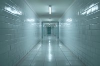 Empty long hospital corridor with white tiled walls and fluorescent lighting creating an eerie atmosphere, perfect for medical, horror or institutional design projects.