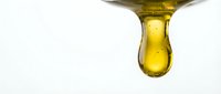 Golden oil droplet suspended from a metallic spout against white background, isolated for cosmetics, skincare, and wellness product design use.