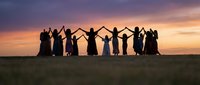 Group of people holding hands in circle silhouetted against dramatic sunset sky. Community teamwork and unity concept for social projects and events.
