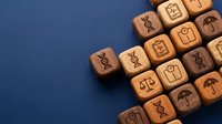 Wooden blocks with engraved healthcare and insurance icons arranged on a blue background, representing medical services, life insurance, and health management concepts.