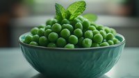 Fresh green peas in turquoise ceramic bowl decorated with mint leaves, shallow depth of field, soft natural lighting creates appetizing food composition.