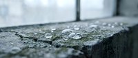 Water droplets on dark stone surface with shallow depth of field creating atmospheric mood for spa wellness and natural texture backgrounds.