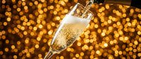 Champagne glass with sparkling bubbles pouring against golden bokeh lights, perfect for celebration, party, and festive event marketing materials.