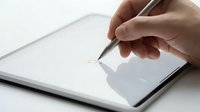 Hand holding stylus pen drawing on digital tablet screen for creative design work and digital art projects.