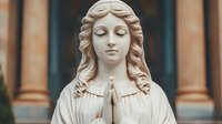 Serene marble statue of praying female figure with flowing hair and closed eyes, classical religious sculpture against architectural columns background.