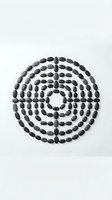 Black oval stones arranged in concentric circles forming spiral pattern on white background for meditation wellness and zen design concepts.