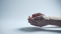 Cupped hands in protective gesture against soft light background symbolizing care, support, hope and spiritual protection in minimalist composition.