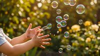 Child's hands reaching toward floating soap bubbles in sunny garden with yellow flowers and green foliage, capturing playful outdoor summer fun and carefree childhood moments.