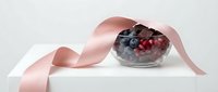 Elegant gift box with fresh berries and pink ribbon on white surface, perfect for holiday packaging and celebration designs.