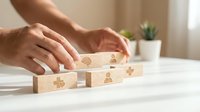 Male hands carefully placing wooden blocks with puzzle pieces in modern office setting for teamwork and problem-solving concepts in business strategy.