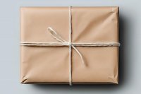 Minimalist wrapped package in kraft paper with simple twine bow on light background, top view. Clean composition for gift giving and sustainable packaging design.