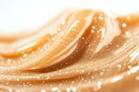Flowing golden waves with sparkling particles create luxurious abstract background in warm caramel tones, suitable for cosmetic and beauty product advertising.