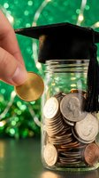 Hand dropping coin into graduation cap topped jar filled with money representing education savings and tuition fund planning for college expenses.