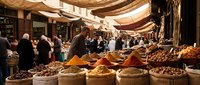 Traditional Middle Eastern spice market with vendors selling colorful spices, nuts and dried fruits in burlap sacks under fabric canopies for culinary themes.