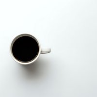 White ceramic coffee mug filled with black coffee viewed from above on clean white background for minimalist design projects.