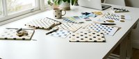 Young female designer working on color palette selection and pattern development at bright workspace with natural light, suitable for creative industry, design education, and branding projects.