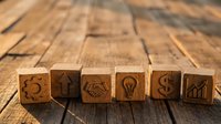 Wooden blocks with business icons including gear, handshake, lightbulb and growth chart arranged on rustic wood surface for corporate presentations.