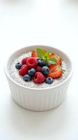 Chia seed pudding topped with fresh berries and mint in white ceramic bowl on clean background for healthy breakfast and superfood concepts.