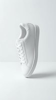 White leather sneaker balanced on its sole against a clean light background, showcasing minimalist style and modern casual footwear design.