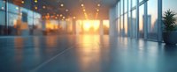 Modern empty office space with panoramic windows and warm sunset light creating atmospheric bokeh effect on reflective floor, suitable for business concepts.