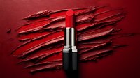 Red lipstick standing on smeared dark red creamy texture background, dramatic cosmetic product photography for beauty and makeup advertising campaigns.