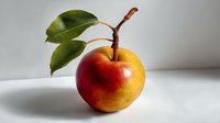 Fresh ripe pear with green leaves on stem against white background, showcasing vibrant red and yellow gradient skin texture.