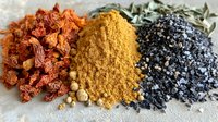 Colorful spice composition with dried red chili peppers, yellow curry powder and black salt on white surface, macro food photography for culinary design.