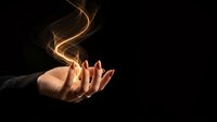 Open palm with glowing golden energy swirls floating above hand against dark background for spiritual healing and magic concepts.