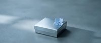 White gift box with blue ribbon bow on gray surface for special occasions and celebrations.