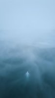 Solitary figure standing in dense fog surrounded by misty forest landscape, creating atmospheric and mysterious mood for conceptual projects.