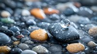 Water drop on black stone with colorful pebbles in background, macro photography showing reflection and refraction with morning dew and natural light.