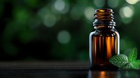 Amber glass essential oil bottle with fresh mint leaf on dark surface against blurred green bokeh background, wellness and aromatherapy concept.