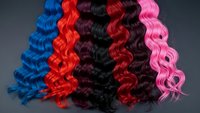 Colorful curly hair extensions in blue, red, black, burgundy and pink arranged in wavy strands for beauty salon, fashion styling and hair transformation concepts.