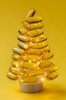 Golden vitamin capsules arranged in Christmas tree shape with warm lights on yellow background for holiday health and wellness marketing campaigns.