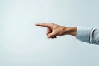 Male hand in business shirt sleeve pointing finger to side against light background, showing direction, leadership or blame gesture for business concepts.