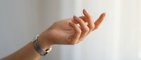Open palm hand gesture with bracelet on wrist against neutral background, suitable for wellness, spirituality, and acceptance concepts.