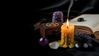 Mystical altar setup with burning candle, crystals, pentagram box and open book for spiritual rituals and witchcraft practices on dark background.