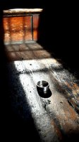 Silver ring on weathered wooden surface with dramatic light and shadow creating moody atmosphere for jewelry photography.