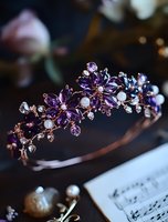 Elegant bridal tiara with purple crystal flowers, pearls and rose gold details on dark background, luxury wedding hair accessory with floral design pattern.