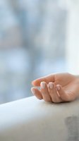 Woman's hand with natural manicure resting on beige fabric, soft blurred background. Suitable for beauty, wellness, skincare, and lifestyle design projects.