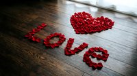 Red rose petals arranged in a heart shape and the word love on a wooden floor, romantic Valentine's Day decoration concept.