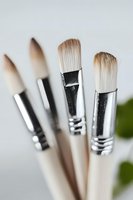 Professional art brushes with silver metal ferrules and natural bristles arranged in soft focus composition against light background. For creative and art supply concepts.