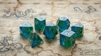 Emerald green translucent polyhedral dice set with silver numbers on vintage parchment background for tabletop gaming and role-playing adventures.